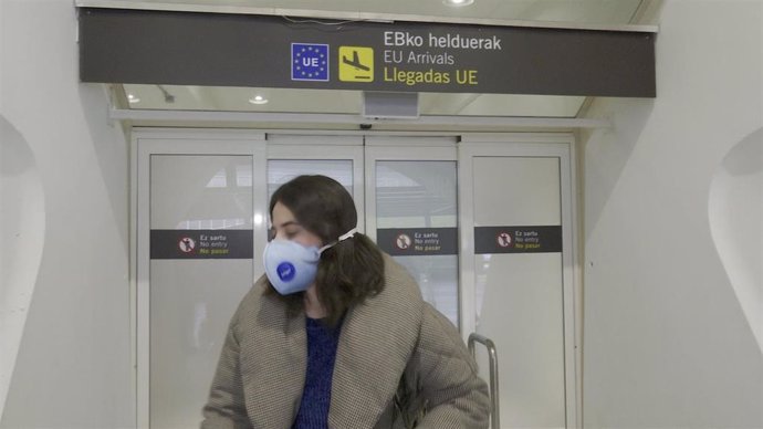 Pasajera, con mascarilla, llega al aeropuero de Bilbao procedente de Milán.
