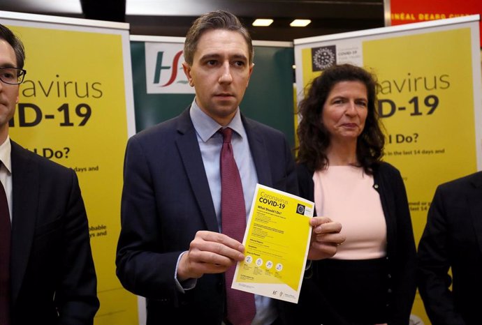 28 February 2020, Ireland, Dublin: UK Minister for Health Simon Harris (C) holds a leaflet which forms part of the public awareness campaign for COVID-19 (Coronavirus) at the baggage hall of Terminal 2 of the Dublin Airport. Photo: Brian Lawless/PA Wire