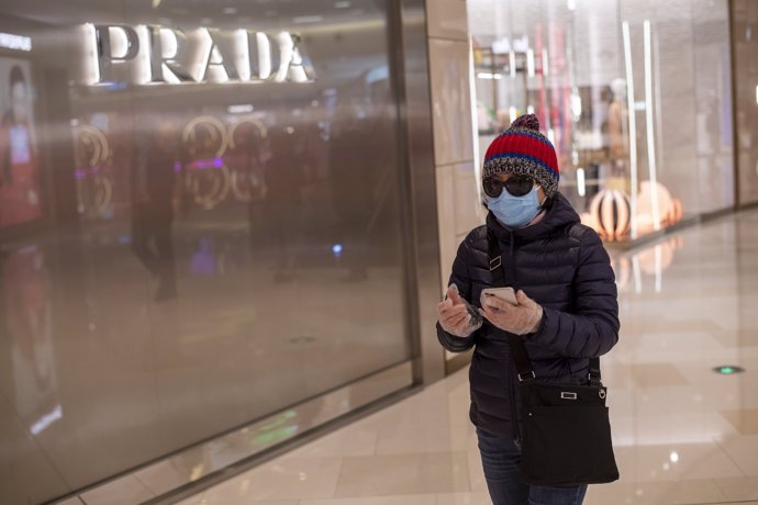 February 26, 2020 - Shanghai, China: A female shopper wears a surgical mask and sunglasses and plastic gloves outside the Prada store at the iapm luxury mall. (Dave Tacon/Contacto)