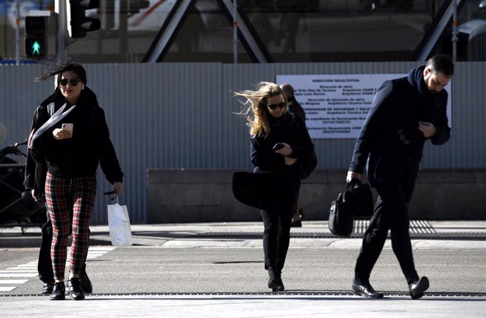 Tres personas caminan por Madrid con la presencia de la borrasca Jorge que desde el sábado se hace notar en la península dejando rachas muy fuertes de viento, lluvias y un frente frío, en Madrid (España), a 2 de marzo de 2020.
