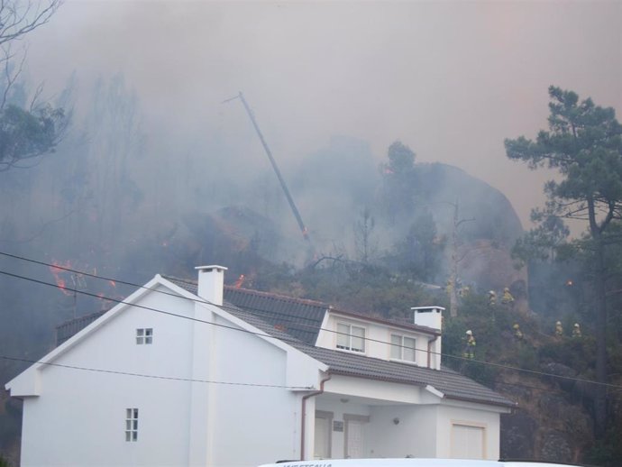 Brigadistas apagan fuego en las inmediaciones de las casas en O Ézaro