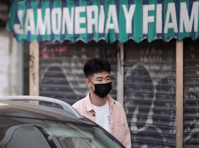 Un joven de rasgos asiáticos camina por el distrito madrileño de Usera protegiendo su rostro con mascarillas tras el anuncio de decenas de casos de pacientes con coronavirus en España y varios en la capital, en Madrid (España), a 28 de febrero de 2020.