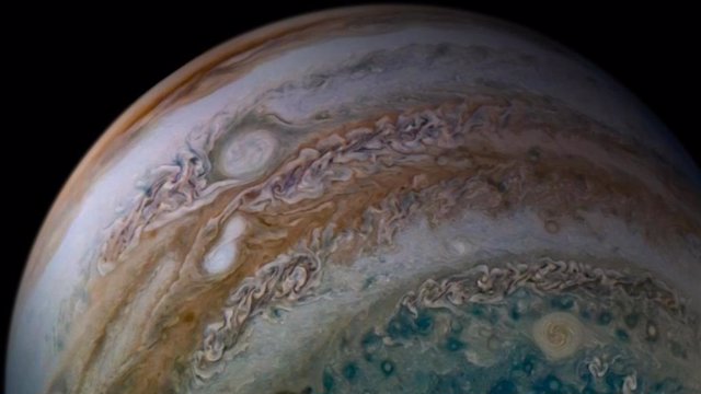 Esta vista de la atmósfera de Júpiter desde la nave espacial Juno de la NASA incluye algo notable: dos tormentas atrapadas en el acto de fusión.