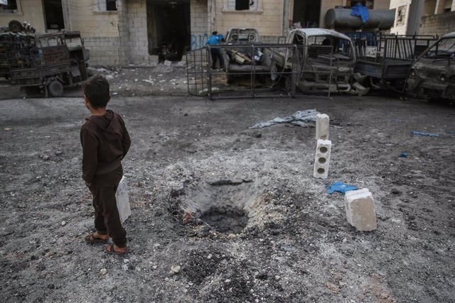 Un niño junto a un agujero provocado por los ataques sobre Idlib (Siria)