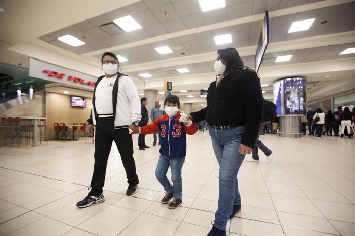 29 February 2020, Ecuador, Quito: Family members wear mouthguards at Mariscal Sucre International Airport. The first case of coronavirus was confirmed in the South American country on Saturday. Photo: Juan Diego Montenegro/dpa