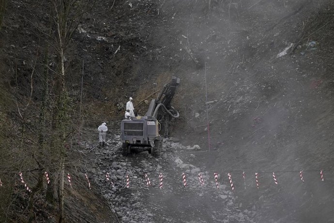 Una excavadora y dos operarios trabajan en las labores de búsqueda de los dos trabajadores sepultados tras el derrumbe del vertedero de Zaldibar.