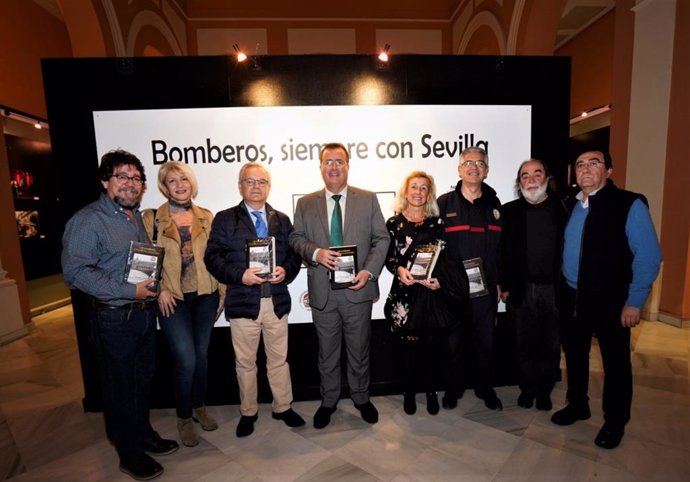 Participantes en la inauguración de la exposición fotográfica 'Bomberos siempre con Sevilla' en el Ayuntamiento de Sevilla.