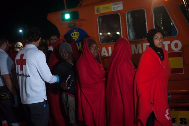 18 July 2019, Spain, Malaga: Migrant women draped in red blankets disembark from a rescue vessel after their arrival at the Port of Malaga