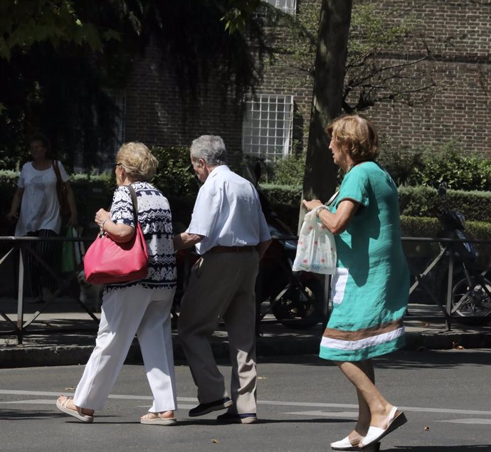 Un grupo de ancianos, cruzan un paso de peatones en una calle de Madrid.