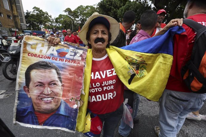Un hombre sostiene una fotografía de Hugo Chávez.