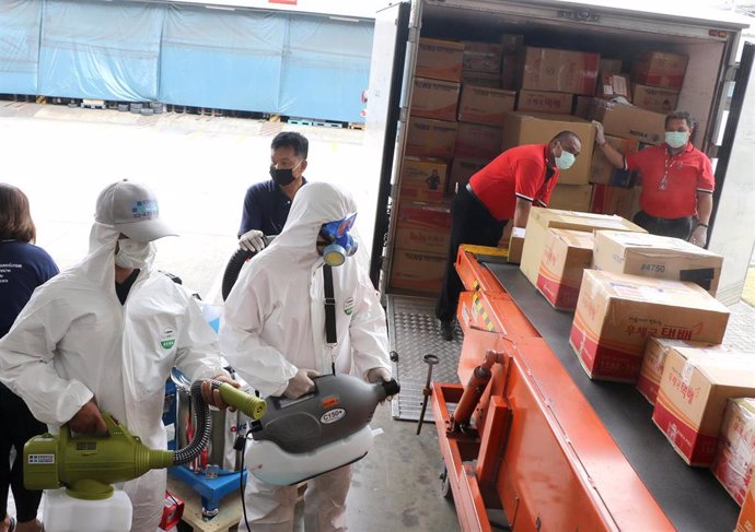Trabajadores en Tailandia desinfectan paquetes