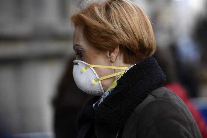 Una mujer con mascarilla se dirige a la Basílica de Jesús de Medinaceli con motivo de la tradición de venerar y dar culto a la imagen del Cristo el primer viernes de marzo