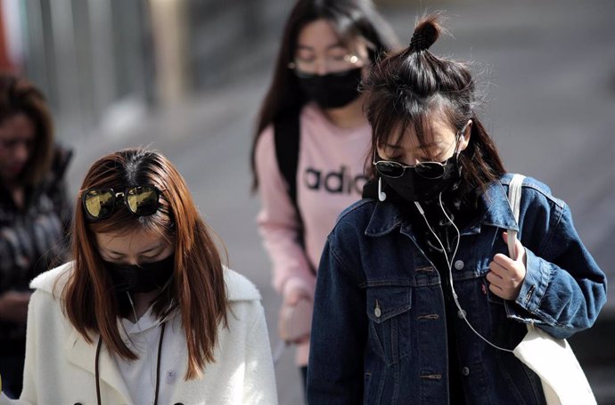 Tres jóvenes de rasgos asiáticos caminan por el distrito madrileño de Usera protegiendo su rostro con mascarillas