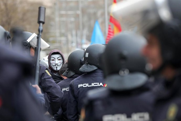 Agentes de la Policía Nacional frente a los manifestantes con máscaras de Anonymous y banderas de España en las inmediaciones del Congreso