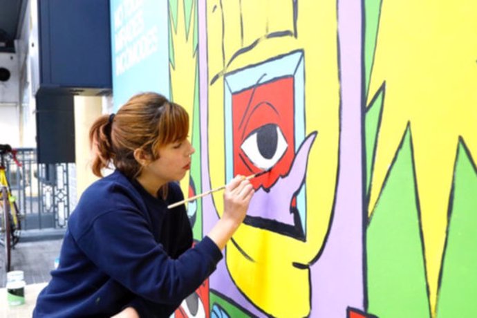 La illustradora Cristina Daura mentre pinta un mural en el marc de la campanya 'Tolerncia Zero' d'FGC, el 7 de mar del 2020. (Horitzontal)