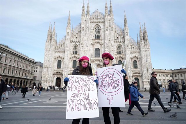 Dos mujeres celebran el 8 de Marzo ante la Catedral de Milán protegidas con mascarillas por el coronavirus