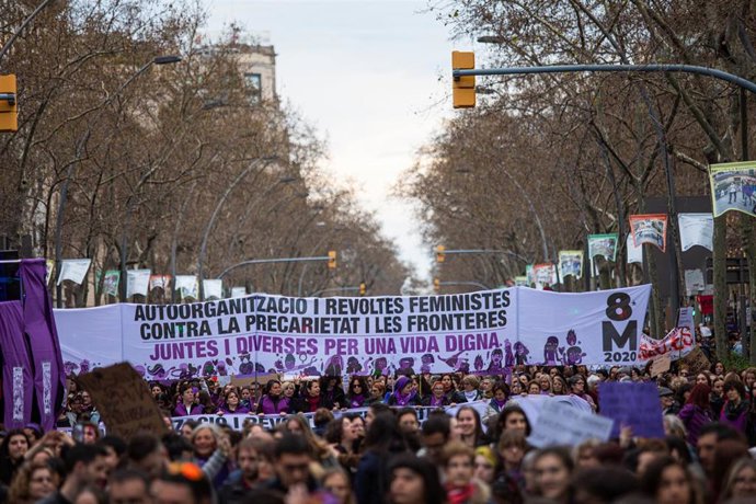 Manifestantes con una gran pancarta en la que pone "Autoorganización y revueltas feministas contra la precariedad y las fronteras. Juntas y diversas por una vida digna" del 8M (Día Internacional de la Mujer), en Barcelona a 8 de marzo de 2020.