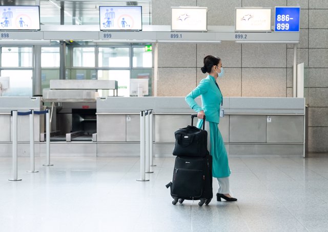 09 March 2020, Hessen, Frankfurt_Main: A flight attendant walks through Terminal 2 of Frankfurt Airport with a face mask as many flights have been cancelled due to the coronavirus. Photo: Silas Stein/dpa