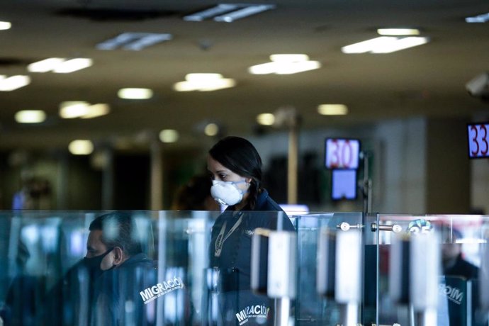 Empleada del aeropuerto internacional de Bogotá con una mascarilla por el coronavirus