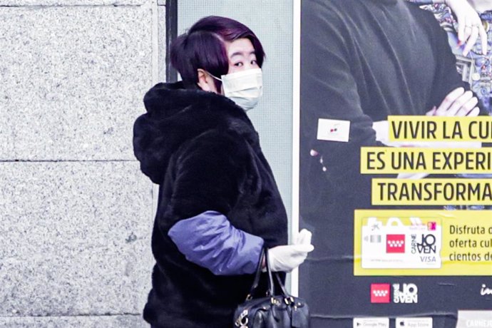 Una mujer de rasgos asiáticos pasea con una mascarilla por una calle de Madrid tras el incremento de casos de coronavirus en la Comunidad de Madrid, en Madrid (España) a 9 de marzo de 2020.