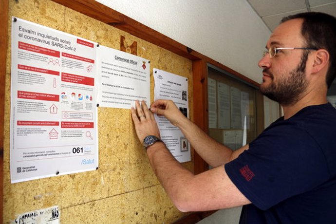 Pla mitj on es pot veure l'alcalde de Castellser, Marcel Pujol, penjant un cartell informatiu sobre el coronavirus a la cartellera dels baixos de l'Ajuntament, el 10 de mar de 2020. (Horitzontal)