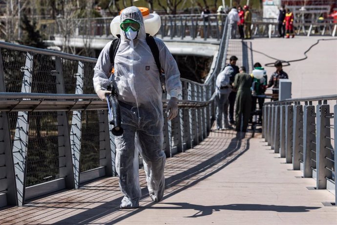 Un trabajador desinfecta un puente en Teherán