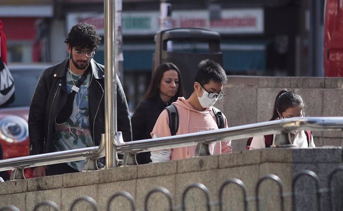 Un joven de rasgos asiáticos entra en el metro del distrito madrileño de Usera protegiendo su rostro con una mascarilla.
