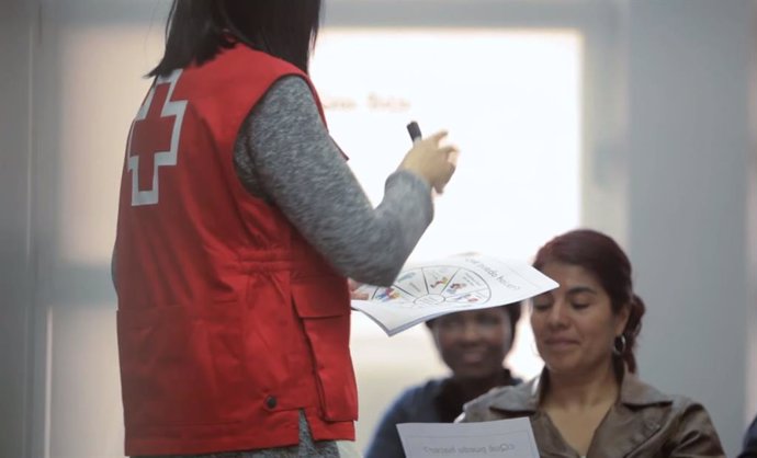 Una voluntria de Creu Roja atén dones usuries de l'entitat.