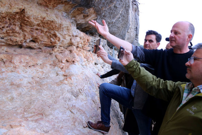 El director del Centre d'Interpretació d'Art Rupestre d'Ulldecona, Agustí Vericat, al centre, explica els detalls de la nova app davant les pintures rupestres de l'Abric I. Imatge del 10 de mar de 2020. (horitzontal)