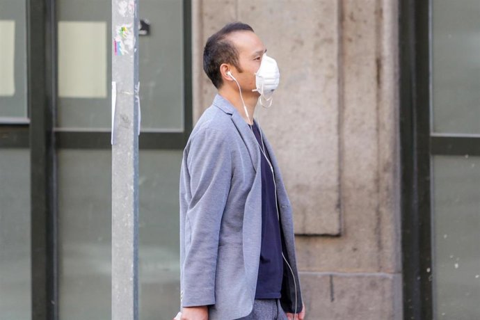 Un transeúnte utiliza una mascarilla para caminar en pleno brote de coronavirus.