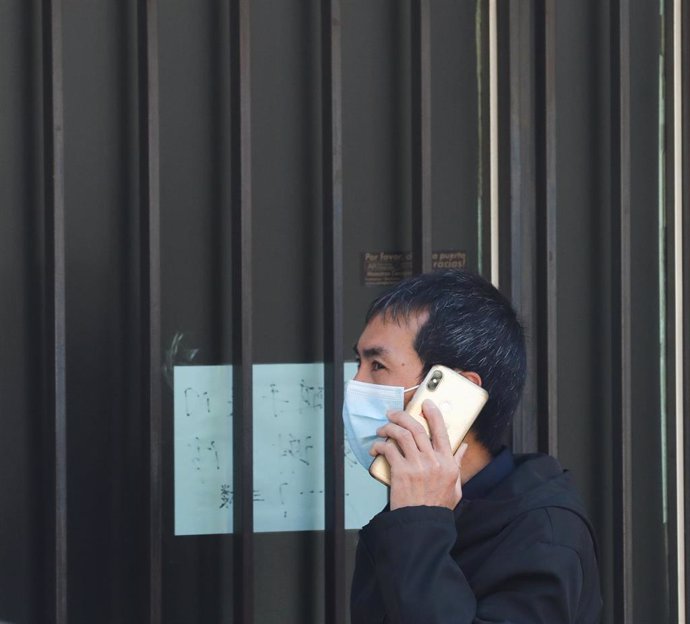 Un hombre de origen asiático pasea con mascarilla por una tienda asiática cerrada como consecuencia del coronavirus, en el barrio de Usera/Madrid (España), a 11 de marzo de 2020.
