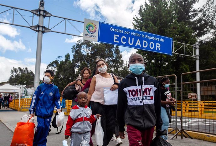 Los miembros de una familia, ataviados todos ellos con mascarillas, cruzan la frontera de Colombia con Ecuador.