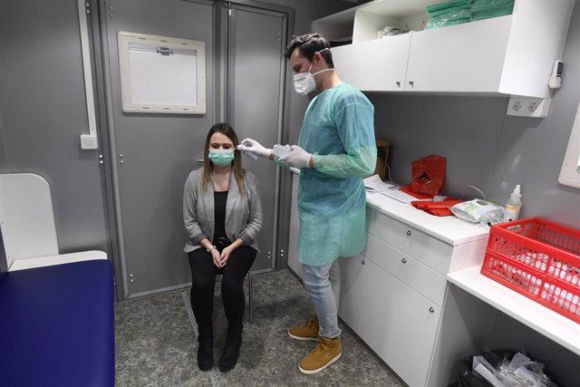 10 March 2020, Erkelenz: A nurse and an employee demonstrate how to take the temperature of a patient in the mobile ward of the Hermann Josef Hospital at Willy Stein Stadium, amid the Coronavirus outbreak. Photo: Roberto Pfeil/dpa