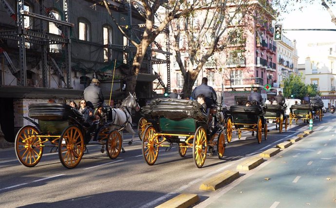 Turistas paseando en coche de caballo por las calles de Sevilla