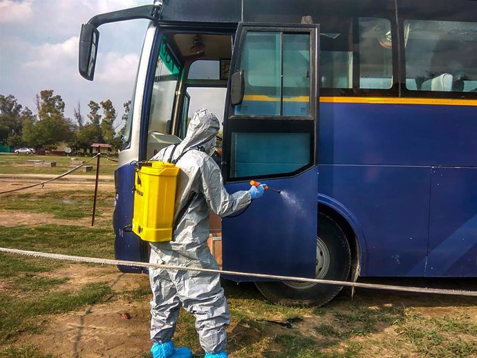 Un trabajador sanitario desinfecta un autobús en Nueva Delhi