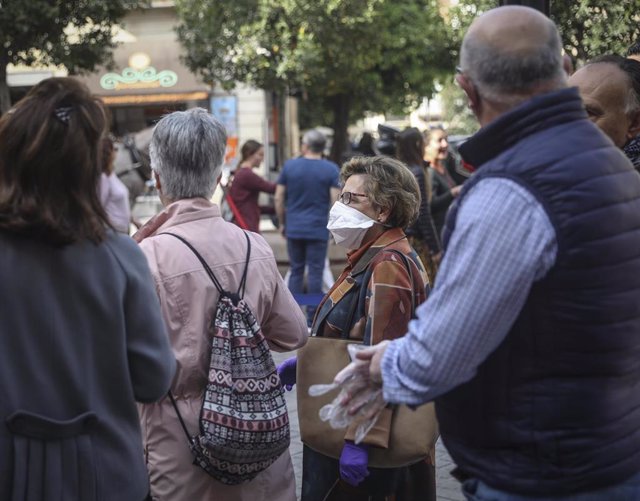 Una mujer con mascarilla y guantes espera su turno en la cola para acceder en al Real Alcázar. En Sevilla, (Andalucía, España), a 12 de marzo de 2020.
