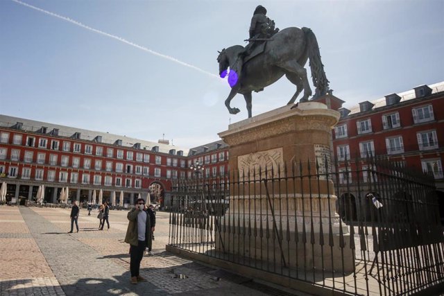 Un hombre con mascarilla pasea cerca de la estatua equestre de Felipe III en la Plaza Mayor de Madrid