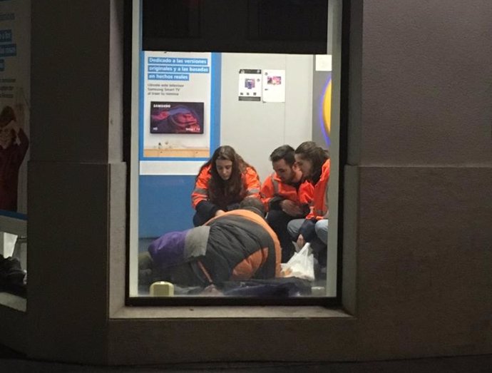 Voluntarios de la UVI Social de Cáritas en Córdoba atienden a un sin techo en un cajero automático.