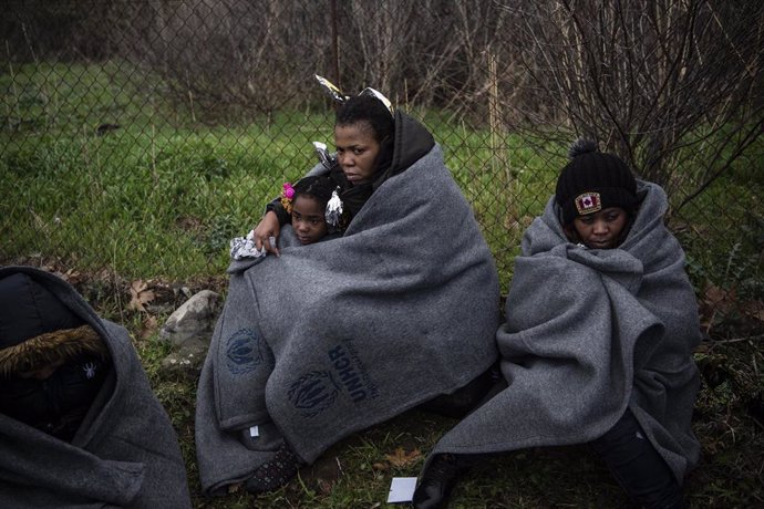 29 February 2020, Greece, Lesbos: Migrants from Africa sit wrapped with blankets on the beach of the village of Skala Sikamias after their arrival from Turkey in a rubber dinghy. Photo: Angelos Tzortzinis/dpa