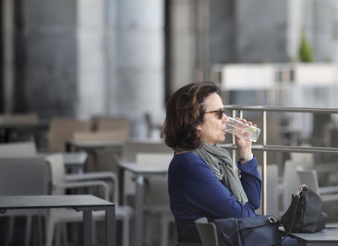 Una mujer toma un refresco en una terraza.