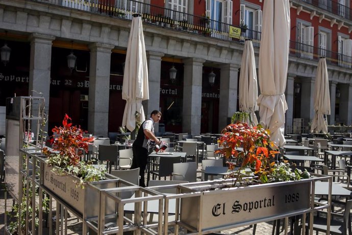 Un empleado de un bar en la Plaza Mayor de Madrid comienza a recoger la terraza un día antes de que se cierre toda la hostelería para frenar contagios por coronavirus, en Madrid (España) a 13 de marzo de 2020.