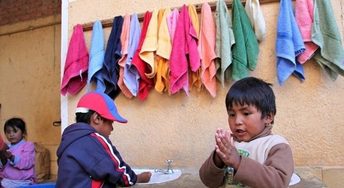 Dos niños en Bolivia se lavan las manos en una estación apoyada por UNICEF.