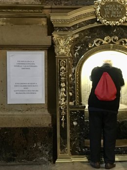 Un sacerdota realiza una reverencia frente a la Columna de la Virgen del Pilar en lugar de besarla por la recomendaciónfrente al coronavirus