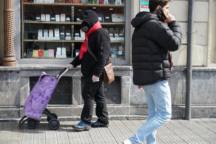 Transeúntes pasen por Bilbao tras la declaración de Estado de Alarma por coronavirus