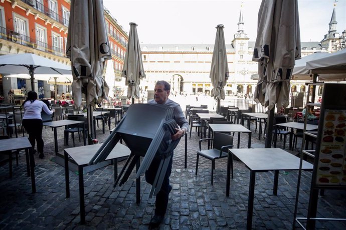 Varios empleados de un bar de la Plaza Mayor de Madrid recogen la terraza un día antes de que se cierre toda la hostelería para frenar contagios por coronavirus, en Madrid (España) a 13 de marzo de 2020.
