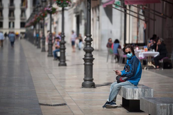 14 March 2020, Spain, Malaga: A man wearing a face mask as a precaution against the spread of Coronavirus (Covid-19)sits on a bench in the downtown of Malaga.  Imagen de archivo