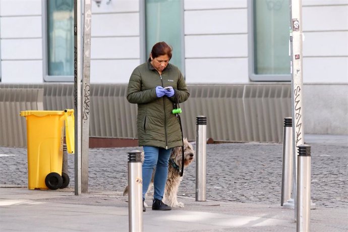 Una mujer pasea con su perro por una calle de Madrid durante la crisis del coronavirus en Madrid