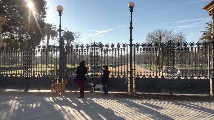 Dues dones passegen el gos per l'entrada del Parc de la Ciutadella de Barcelona, tancat