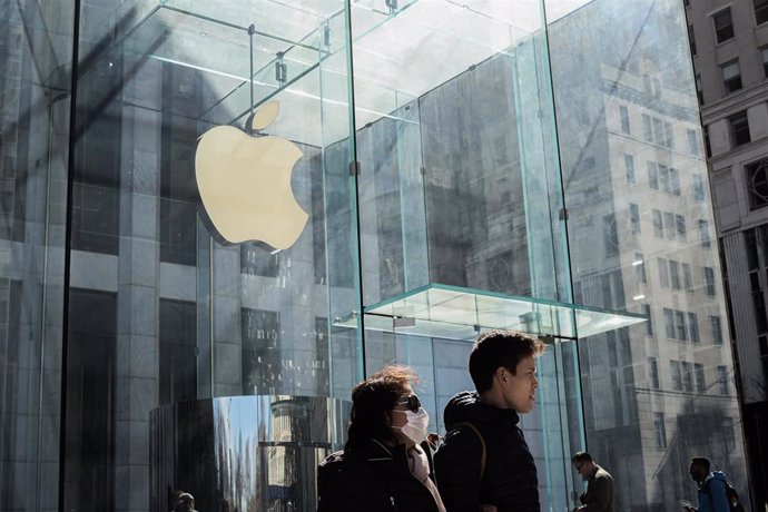 March 14, 2020 - New York, New York, United States: A couple wearing mask strolling by the Apple store on Fifth Avenue. Apple has decided to shut down all its stores. The City of New York is under intense pressure due to the Coronovirus pandemic. Stores