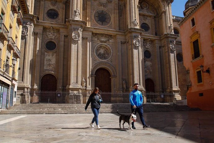 Dos ciudadanos pasean a un perro en el entorno de la Catedral. Granada a 16 de marzo del 2020